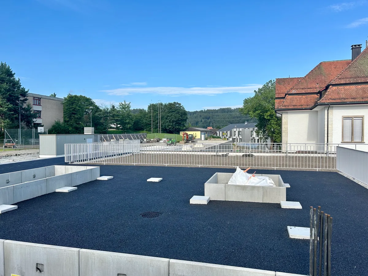 Man sieht die neue Sporthalle zwischen den bestehenden Schulhäusern.